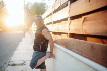 Älterer Mann streckt sich auf Holzwand in Straße — Stockfoto