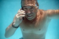 Homem maduro mergulho debaixo de água com smartphone — Fotografia de Stock