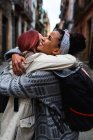 Vue latérale de belles femmes souriantes multiethniques embrassant à la réunion dans la rue étroite avec de vieilles maisons — Photo de stock