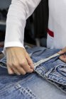Imagem cortada do trabalhador na fábrica têxtil verificando a qualidade das peças de vestuário. Produção industrial — Fotografia de Stock