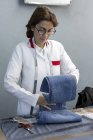 Lavoratrice in fabbrica tessile che controlla la qualità degli indumenti. Produzione industriale — Foto stock