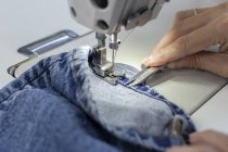 Imagen recortada del trabajador en la costura de fábrica textil en la máquina de coser industrial. Producción industrial - foto de stock