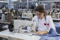 Arbeiterin in einer Textilfabrik näht auf einer Industrienähmaschine. Industrieproduktion — Stockfoto