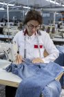 Робоча жінка на текстильній фабриці шиє на промисловій швейній машині. Промислове виробництво — стокове фото