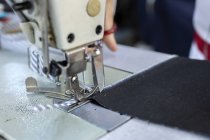 Обрезанный образ рабочего на текстильной фабрике, шитье на промышленной швейной машине. Промышленное производство — стоковое фото