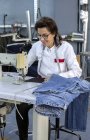 Mujer trabajadora en la costura de fábrica textil en la máquina de coser industrial. Producción industrial - foto de stock