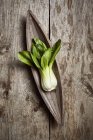 Top view of ripe bok choy placed near wooden plate on shabby lumber table in kitchen — Stock Photo