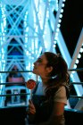 Millennial woman sitting in Ferris wheel and eating lollipop — Stock Photo