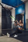 Femme tirant des cordes et s'entraînant dans la salle de gym — Photo de stock