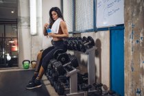 Junge Sportlerin trinkt Wasser in Turnhalle — Stockfoto