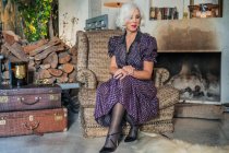 Mulher sênior lindo na sala de estar da casa de campo em estilo vintage — Fotografia de Stock