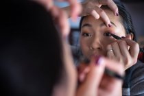 Femme asiatique appliquant eye-liner devant le miroir — Photo de stock