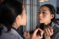 Asiatico donna applicando eyeliner di fronte a specchio — Foto stock