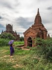 Mujer con paraguas de pie frente al antiguo templo - foto de stock