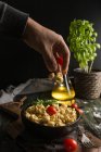 Человек добавляет помидоры в миску с равиоли — стоковое фото