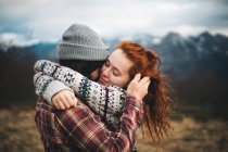 Vista laterale della coppia tenera che abbraccia e lega con gli occhi chiusi nella giornata fredda in montagna — Foto stock