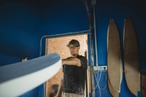 Carpintero haciendo diligentemente tabla de surf en taller - foto de stock