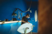 Carpinteiro diligentemente fazendo prancha de surf em oficina — Fotografia de Stock