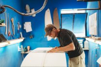 Человек делает доску для серфинга в мастерской — стоковое фото