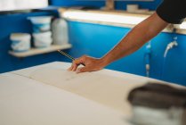 Imagen recortada de artesano haciendo tabla de surf en el taller - foto de stock