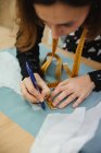 Взрослая женщина, использующая ленту для измерения части одежды на столе во время работы в профессиональной швейной мастерской — стоковое фото