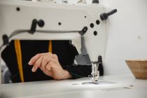 Жінка сидить за столом і робить частину одягу на швейній машині під час роботи в професійній студії — стокове фото