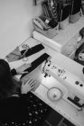 Mulher sentada à mesa e fazendo peça de vestuário na máquina de costura enquanto trabalhava em estúdio profissional — Fotografia de Stock