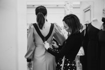 Dressmaker ajuste vestido personalizado en la parte posterior del cliente femenino mientras trabaja en taller profesional - foto de stock