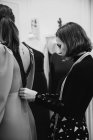 Costureira montagem vestido personalizado na parte de trás do cliente feminino enquanto trabalhava na oficina profissional — Fotografia de Stock