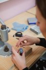 Woman pulling lever of button maker on table in professional dressmaking workshop while making garment — Stock Photo