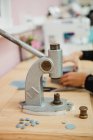 Mujer tirando de la palanca del fabricante de botones en la mesa en taller de confección profesional mientras hace la prenda - foto de stock