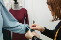 Schneiderin befestigt Knöpfe mit Anstecknadeln am Ärmel des Kleides am Modelarm während der Arbeit in der professionellen Werkstatt — Stockfoto