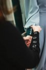 Botones de sujeción del sastre femenino con pasadores en la manga del vestido en el brazo modelo durante el trabajo en el taller profesional - foto de stock
