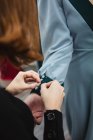 Botones de sujeción del sastre femenino con pasadores en la manga del vestido en el brazo modelo durante el trabajo en el taller profesional - foto de stock