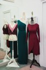 Maniquíes con ropa personalizada de moda colocados cerca del espejo en la esquina del estudio de costura - foto de stock