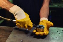 Mãos enluvadas de homem irreconhecível verificando equipamentos e se preparando para o trabalho na oficina — Fotografia de Stock