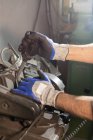 Guantes manos de hombre creando detalle mientras se trabaja en la máquina industrial en el taller - foto de stock