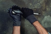 Handschuh-Hände von unkenntlich gemachten Mann schwingen Bohrer während Arbeitsprozess — Stockfoto