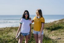 Trendy teen girls with long board in sunshine — стоковое фото