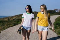 Filles adolescentes à la mode avec une longue planche au soleil — Photo de stock
