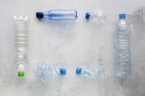 Vista superior de garrafas de plástico e caixas dispostas na superfície de fundo branco — Fotografia de Stock