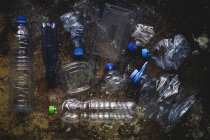 Vista superior de botellas y cajas de plástico dispuestas en suelo contaminado - foto de stock