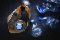 From above dirty paper sack with discarded plastic bottles placed on black background — Stock Photo