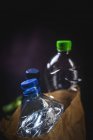 Schmutziger Papiersack mit weggeworfenen Plastikflaschen auf schwarzem Hintergrund — Stockfoto