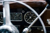 Фрагмент металлического рулевого колеса и приборной панели старого классического автомобиля — стоковое фото