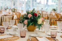 Buquê de flor único simples no vaso na mesa decorada festiva com artigos de vidro no restaurante — Fotografia de Stock
