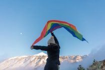 Человек на вершине горы размахивает флагом ЛГБТ — стоковое фото