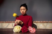 Young Asian woman sitting in shop and working with roses — Stock Photo