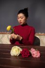 Junge asiatische Frau sitzt im Geschäft und arbeitet mit Rosen — Stockfoto