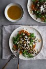 Teller mit leckerem Süßkartoffelsalat und braunem Saucenbesteck zum Mittagessen auf grauen Tisch gestellt — Stockfoto